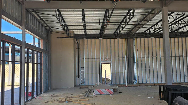 Interior view of a commercial construction site showing exposed framing, unfinished walls, and construction materials, illustrating the ground-up construction process by Kinetic Builders Corp.