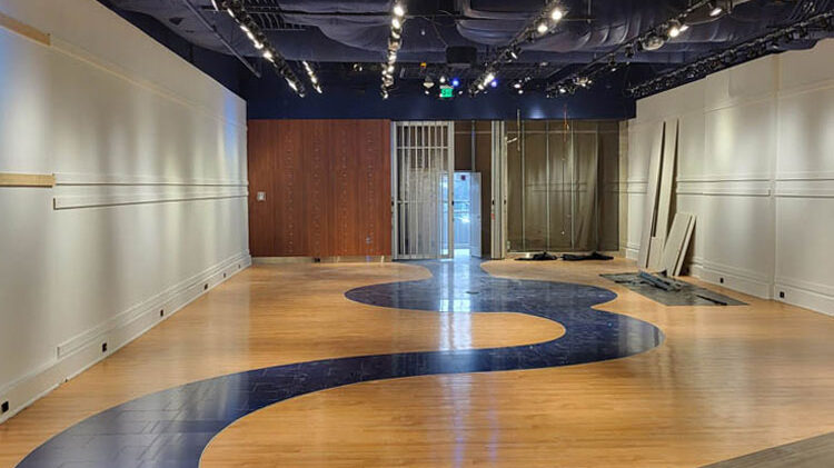 Interior view of a commercial renovation space with polished wooden flooring and a unique blue design element, showcasing the transition from construction to a functional retail environment.