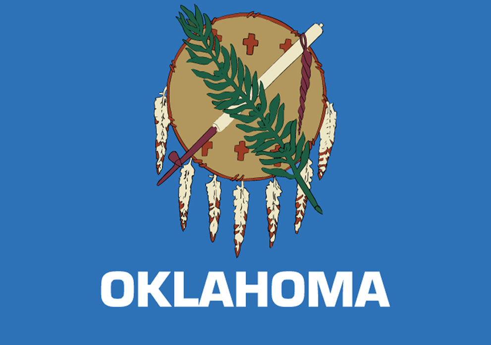 Oklahoma state flag featuring a traditional drum, peace pipe, and feather motifs on a blue background, symbolizing cultural heritage and identity.
