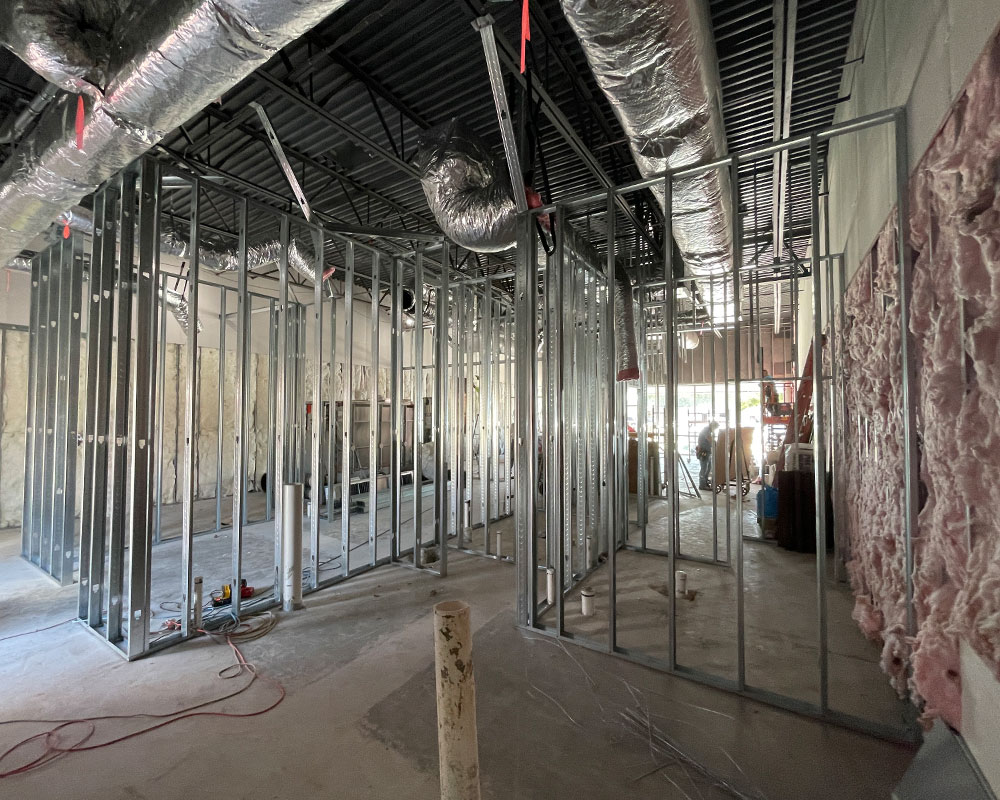 Interior view of a commercial construction site showing metal framing, insulation, and ongoing work, emphasizing the pre-construction phase and groundwork for future builds.