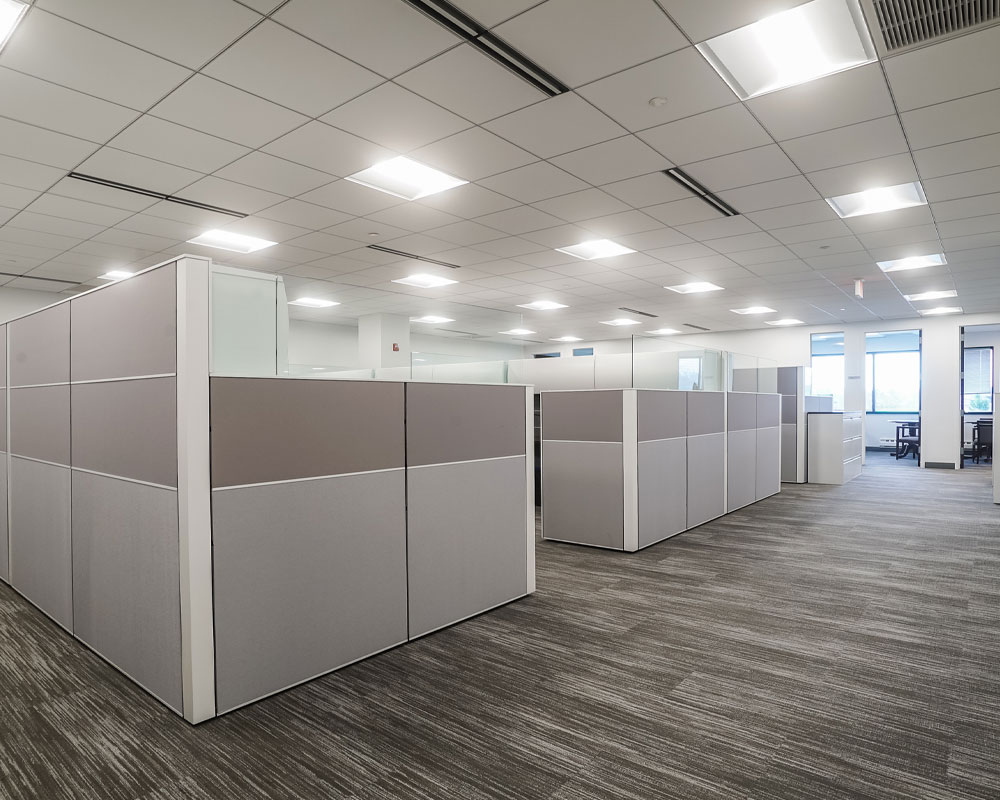 Modern office space with gray cubicles and bright overhead lighting, reflecting Kinetic Builders Corp's project management environment for efficient construction oversight and team collaboration.