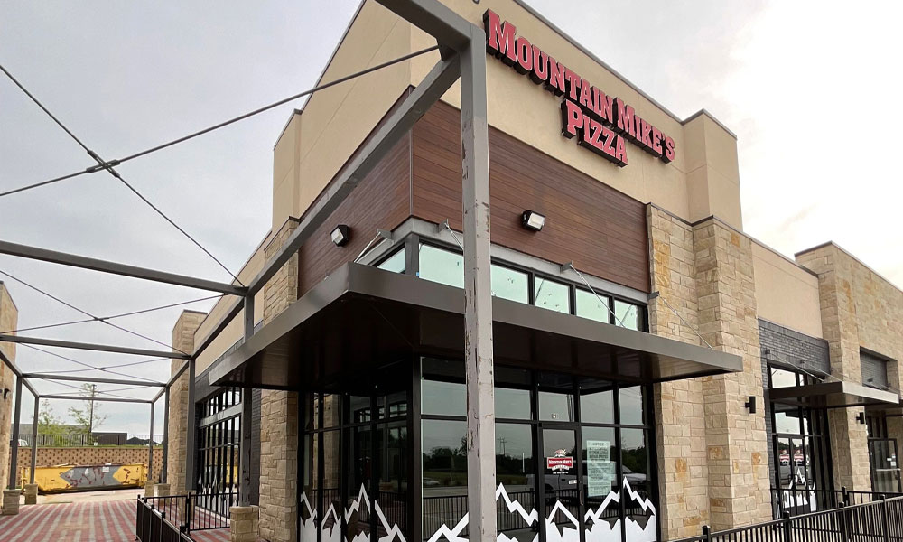 Mountain Mike's Pizza restaurant exterior featuring the brand's signage, modern architecture, and outdoor seating area, representing Kinetic Builders Corp's franchise-focused construction in Texas.