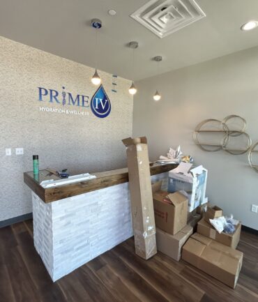 Reception area of PRIME IV Hydration & Wellness with wooden counter, packages, and modern decor, showcasing Kinetic Builders Corp's commercial construction craftsmanship.