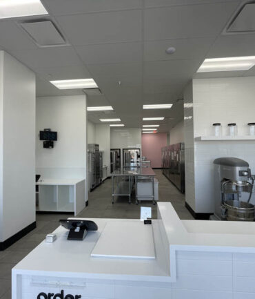 Commercial kitchen interior featuring a service counter, stainless steel appliances, and organized workspace, showcasing Kinetic Builders Corp.'s precision in restaurant build-out projects.