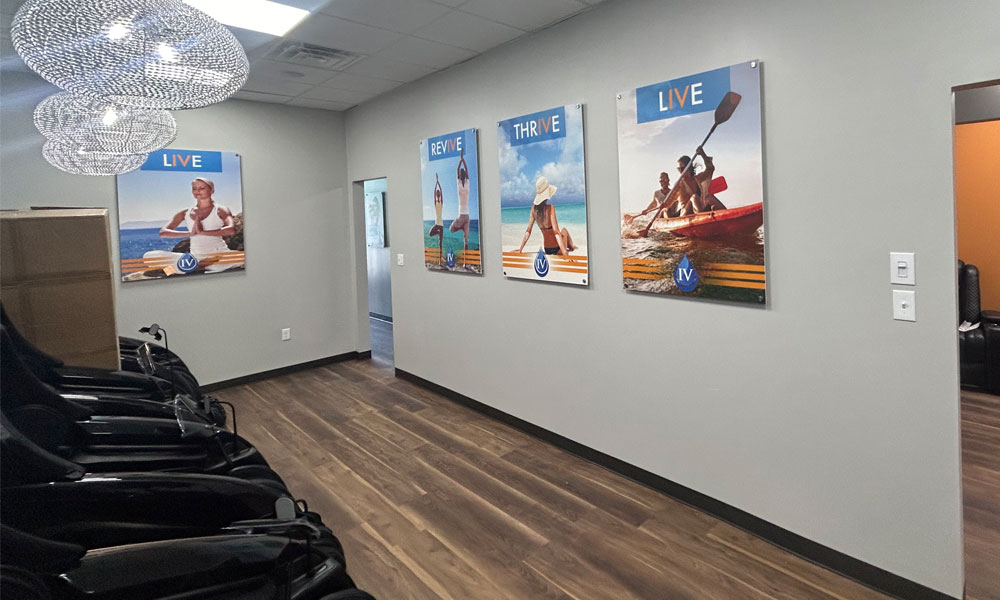 Interior of Prime IV Hydration & Wellness, featuring wellness-themed wall art with "LIVE," "THRIVE," and "REVIVE" slogans, modern lighting, and treatment chairs, emphasizing a tranquil atmosphere for health and wellness services.