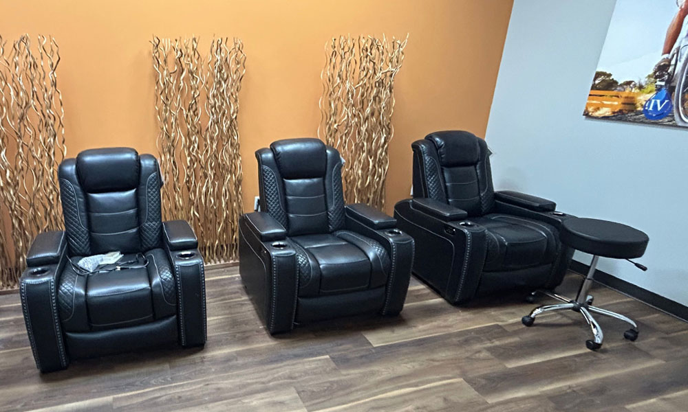 Black leather recliners in a wellness space, surrounded by decorative wooden accents and a modern aesthetic, emphasizing comfort and relaxation for clients at Prime IV Hydration & Wellness.
