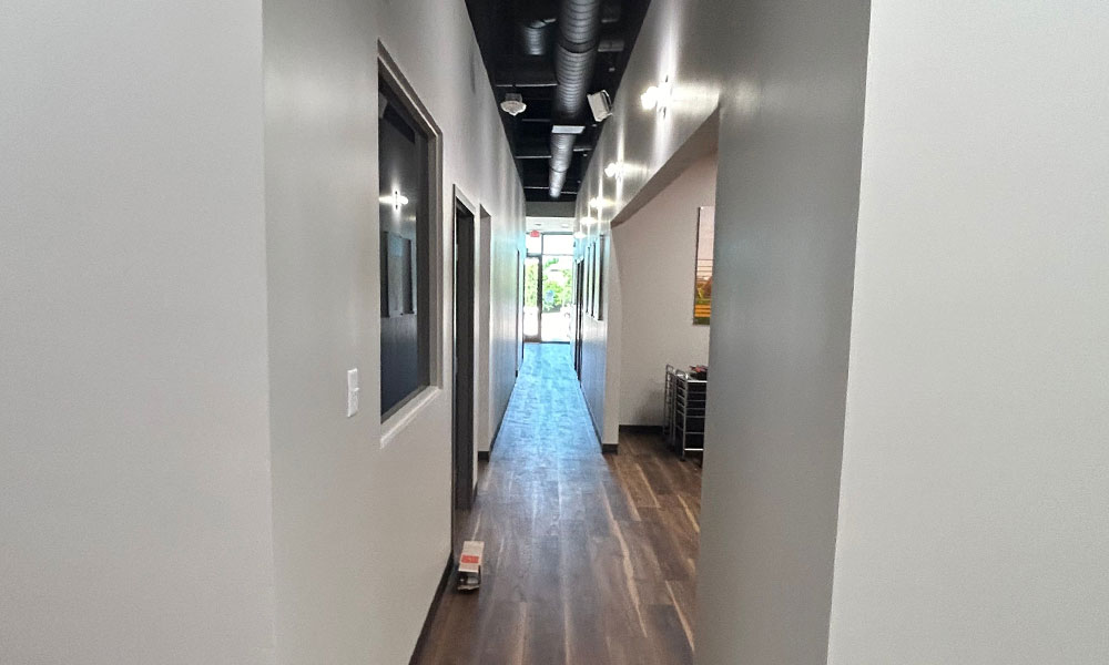 Modern interior hallway of Prime IV Hydration & Wellness, featuring sleek design, natural light from glass doors, and healthcare-compliant construction elements.