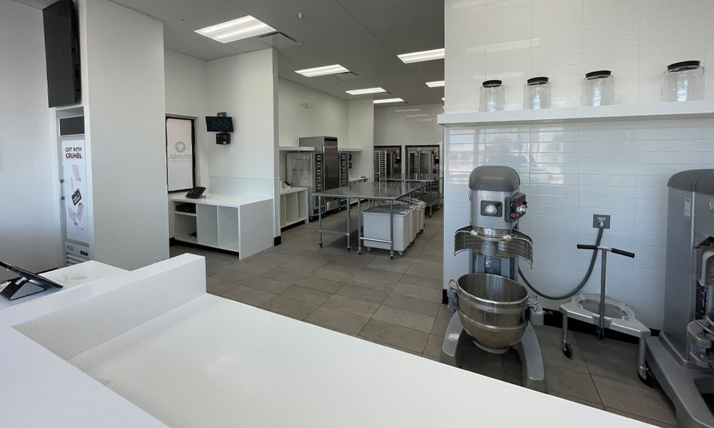 Crumbl Cookies kitchen interior featuring stainless steel equipment, mixing machines, and organized workspace, showcasing Kinetic Builders Corp's franchise-focused construction expertise in food retail build-outs.
