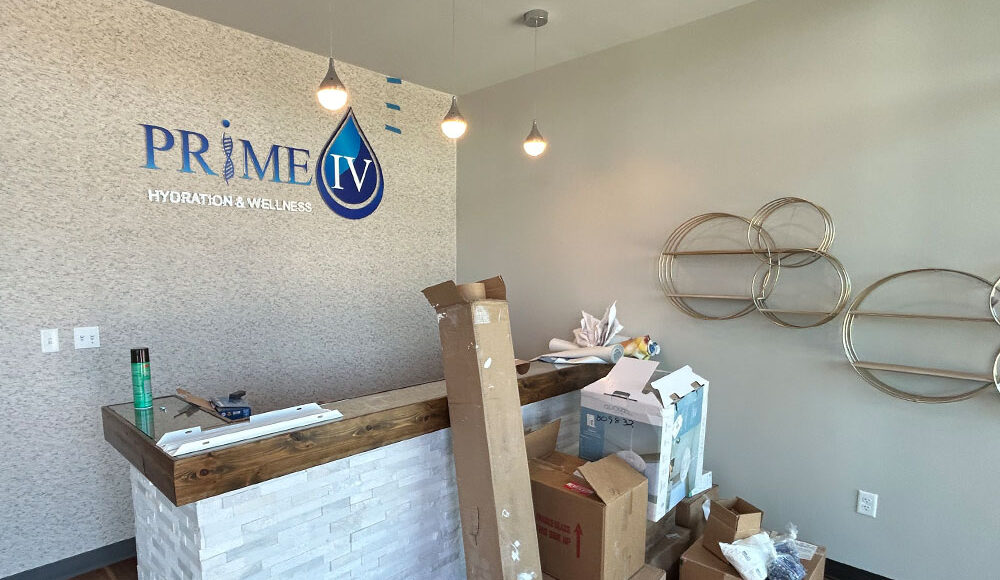 PRIME IV Hydration & Wellness reception area with logo, wooden counter, and construction materials, reflecting Kinetic Builders Corp's tenant build-out expertise.
