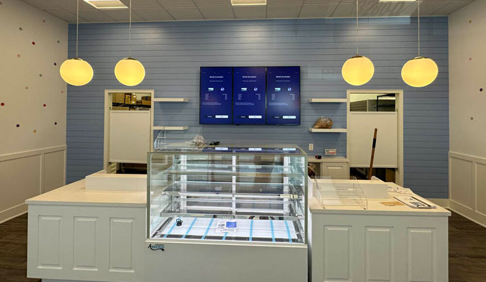 Interior of a modern dessert shop featuring a glass display case, blue wooden walls, and pendant lighting, showcasing Kinetic Builders Corp's tenant build-out project for a retail food franchise.