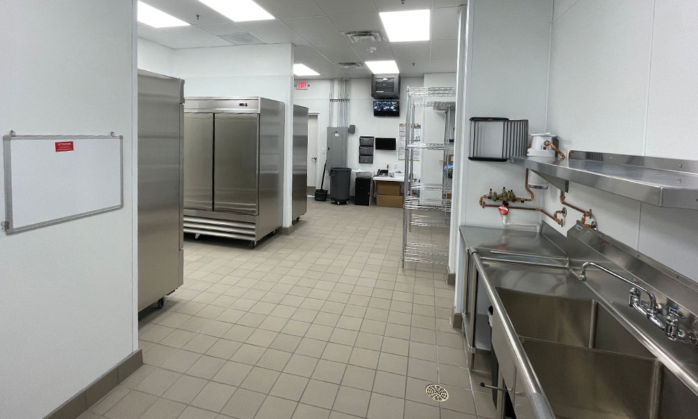 Commercial kitchen interior featuring stainless steel appliances, sinks, and storage areas, designed for Nekter Juice Bar's efficient food service operations.