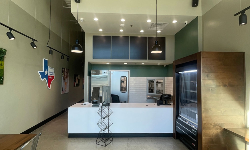Interior view of a Nekter Juice Bar location in Texas, featuring a modern counter design, commercial kitchen equipment, and Texas-themed decor, highlighting the franchise's focus on clean and inviting wellness spaces.