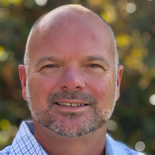 Kevin Caldwell, Director of Business Development at Kinetic Builders Corp, smiling with a blurred natural background, showcasing his approachable leadership style and professional demeanor.