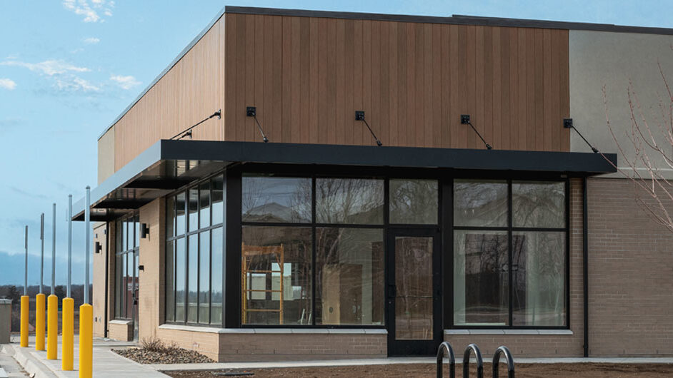 Restaurant exterior with large windows, modern design, and yellow bollards, showcasing potential for customer experience design and location scouting by Kinetic Builders.
