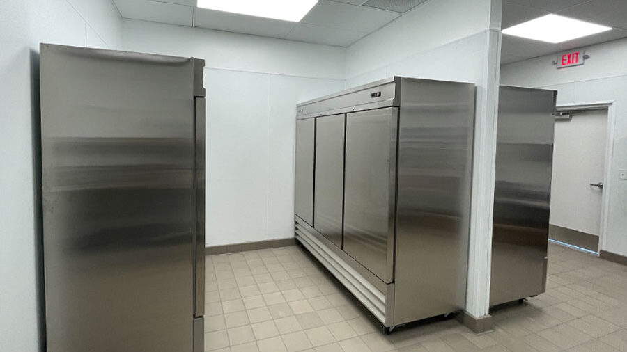 Stainless steel commercial refrigerators in a restaurant kitchen, showcasing food storage solutions and compliance with health safety standards.
