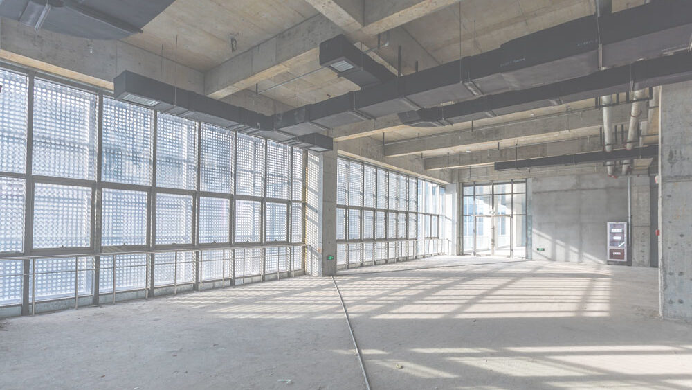 Empty commercial space with large windows and exposed infrastructure, ideal for restaurant tenant improvements and strategic space planning.