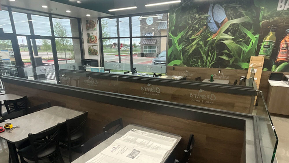 Restaurant interior featuring modern seating and a vibrant mural of fresh ingredients, emphasizing the dining experience in a newly renovated space by Kinetic Builders.