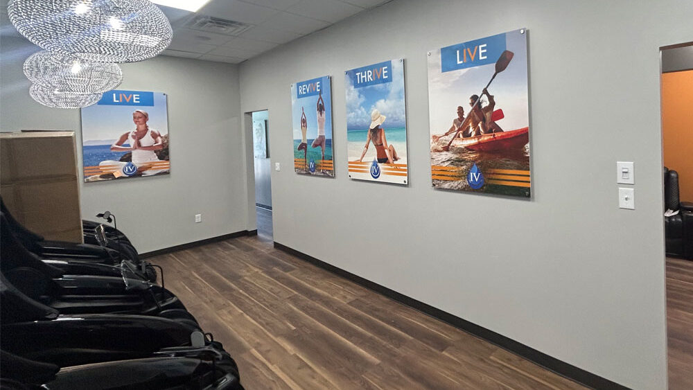 Interior of a modern wellness facility featuring inspirational wall art with themes of health and vitality, showcasing images of active individuals, alongside sleek black chairs and contemporary lighting.