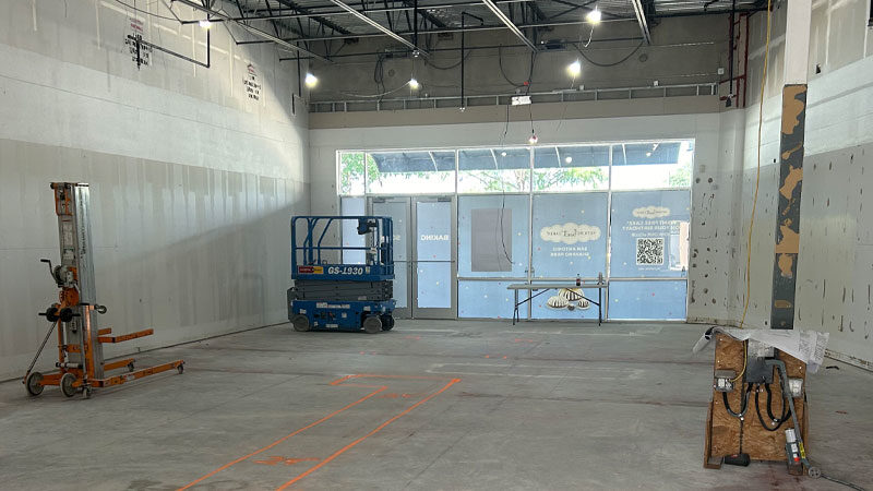 Construction site interior with scaffolding, lift, and marked layout for restaurant build-out, showcasing progress in modern restaurant construction techniques.