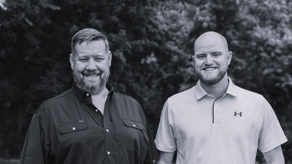Two smiling men standing outdoors, representing Kinetic Builders, showcasing their expertise in restaurant construction and client satisfaction.