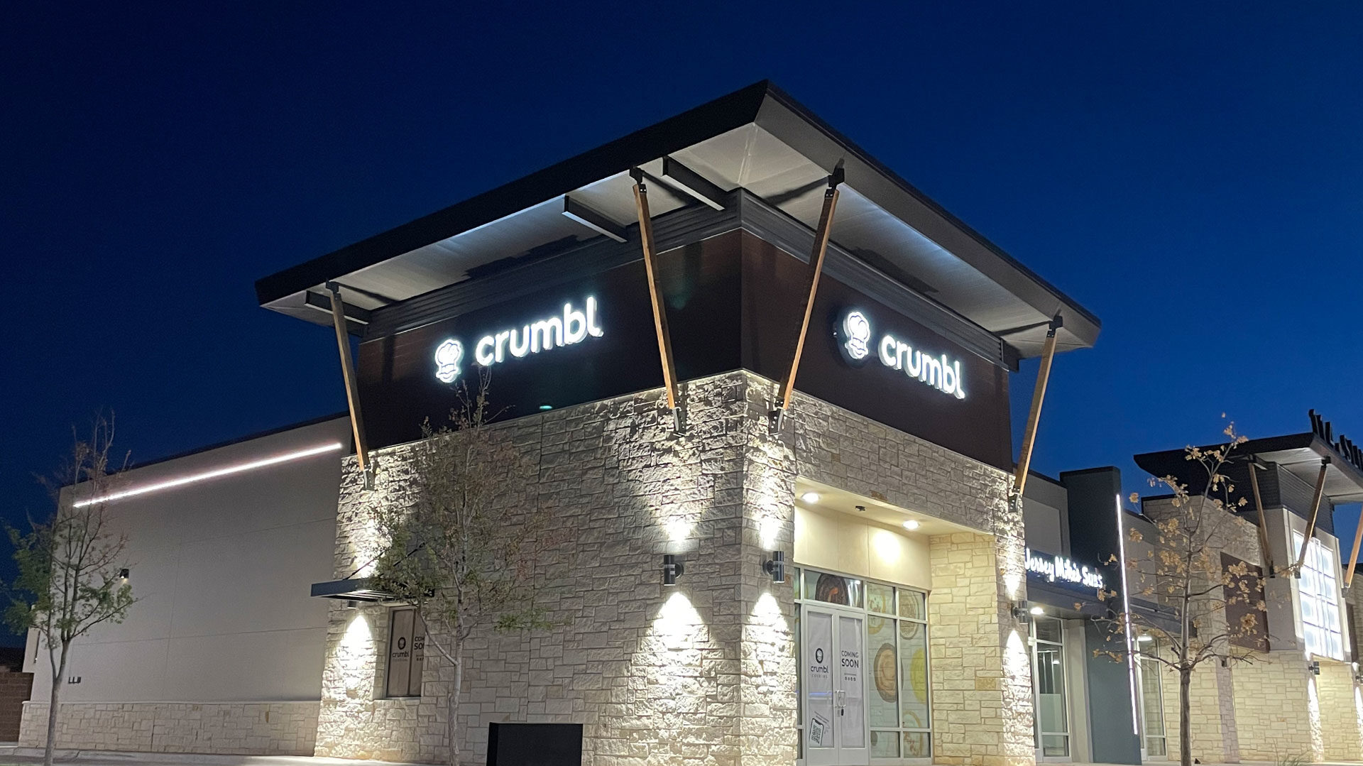 Crumbl restaurant exterior illuminated at night, showcasing modern design and signage, emphasizing Kinetic Builders' expertise in restaurant construction and renovations.